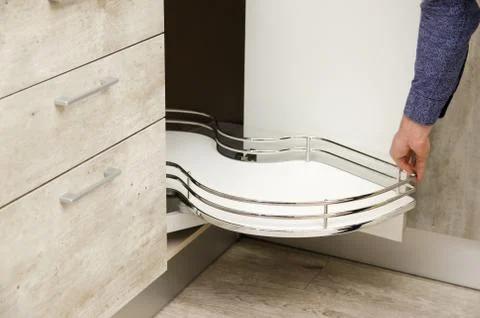 Man pulls a kitchen carousel out from the bottom drawer of a cabinet in a mod Stock Photos