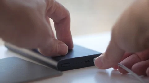 The man pulls out and inserts the cable into the portable charging Stock Footage 99569553
