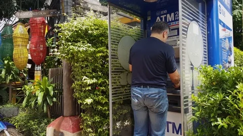 Man pulls out cash at JDB ATM machine, colorful lanterns, wooden sign, Vientiane 스톡 동영상 77071987