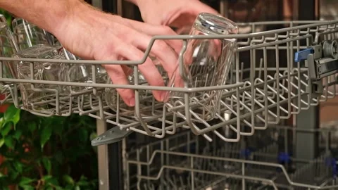The man pulls out the dishwasher basket and unloads clean glasses, cups, bowls Stock Footage 244637881