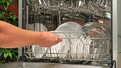 Man pulls out dishwasher basket and unloads clean plates. Release of dishwasher Stock Footage 244637967