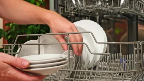 Man pulls out dishwasher basket and unloads clean plates. Release of dishwasher Stock Footage 244638014