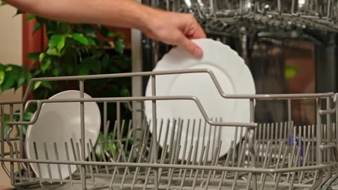 Man pulls out dishwasher basket and unloads clean plates. Release of dishwasher Stock Footage 244803797