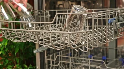 The man pulls out the dishwasher basket and unloads clean glasses, cups, bowls Stock Footage 244803982