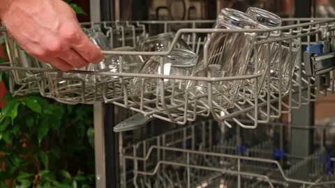The man pulls out the dishwasher basket and unloads clean glasses, cups, bowls Stock Footage 244804157