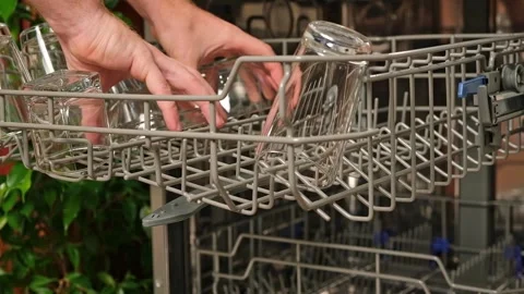 The man pulls out the dishwasher basket and unloads clean glasses, cups, bowls Stock Footage 245209133