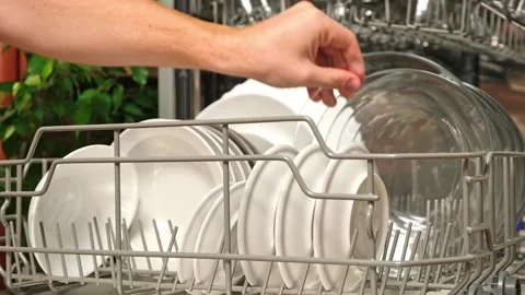 Man pulls out dishwasher basket and unloads clean plates. Release of dishwasher Stock Footage 245209289