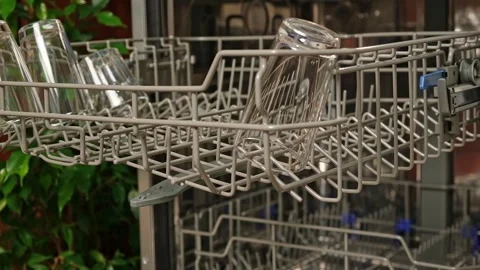 The man pulls out the dishwasher basket and unloads clean glasses, cups, bowls Stock Footage 245657420