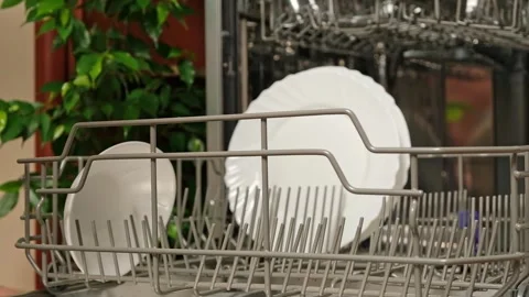 Man pulls out dishwasher basket and unloads clean plates. Release of dishwasher Stock Footage 245657458