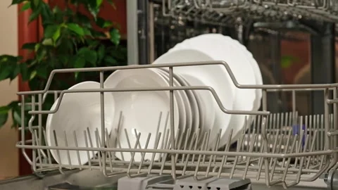 Man pulls out dishwasher basket and unloads clean plates. Release of dishwasher Stock Footage 246070732