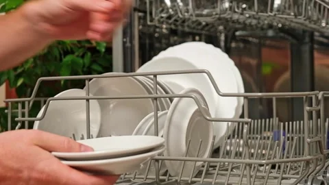 Man pulls out dishwasher basket and unloads clean plates. Release of dishwasher Stock Footage 246641483
