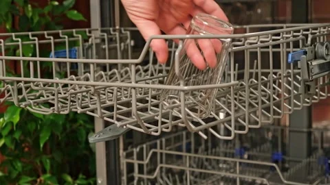 The man pulls out the dishwasher basket and unloads clean glasses, cups, bowls Stock Footage 246641505