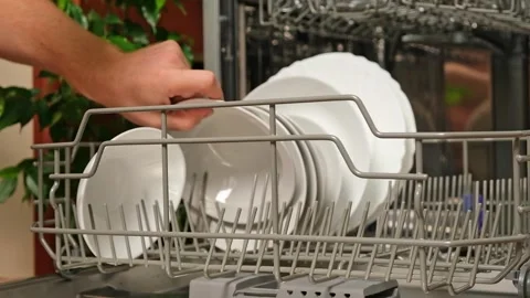 Man pulls out dishwasher basket and unloads clean plates. Release of dishwasher Stock Footage 246915689