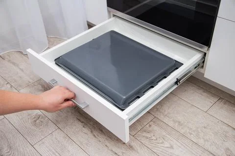 A man pulls out a drawer with baking sheets in the kitchen. A special 写真素材