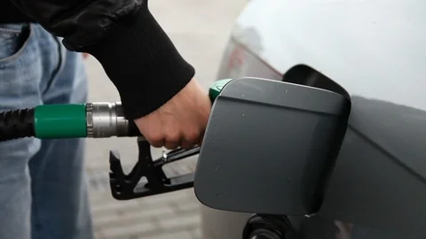 The man pulls out the Fuel nozzle and closes the gas hatch, then the car leaves Stock Footage 116465407