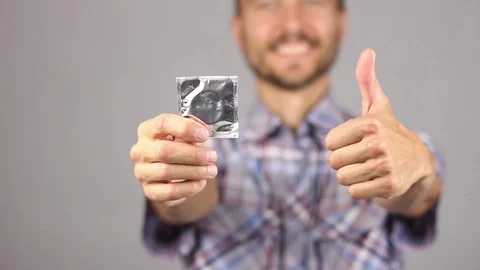 Man pulls out of his pocket a condom, show it in right hand, gesture thumb up Stockbeeldmateriaal 94926960