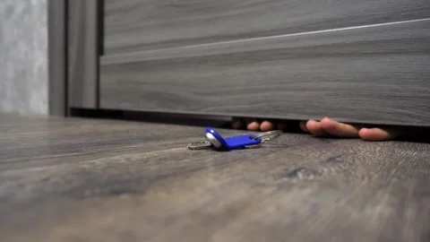 Man pulls out keys through the crack under the door. Stock Footage 262678216