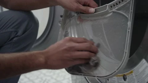 Man pulls out the lint trap from a clothes dryer and pulls the lint off Video stock 147612644