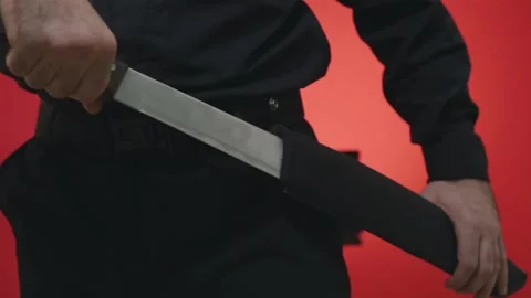 The man pulls out a long saber from his belt holster. Stock Footage 144738213