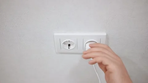 The man pulls out a mobile phone charger from the socket. Stockbeeldmateriaal 150331882