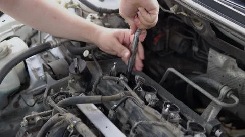 A man pulls out an old spark plug from a car engine Stock Footage 139158373