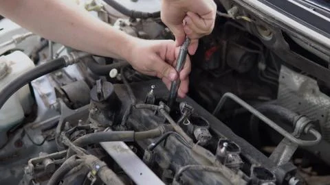 A man pulls out an old spark plug from a car engine 写真素材