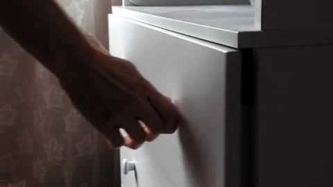 Man pulls out opens and closes dresser drawer with clothes in chest of drawers. 스톡 동영상 347580058