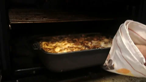 A man pulls out of the oven baked potatoes with meat Video stock 85589989