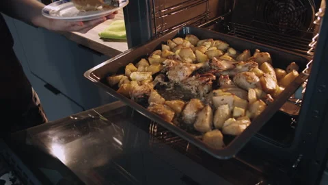 A man pulls out of the oven onto a plate, potatoes and chicken legs Stock Footage 314508745