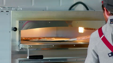 A man pulls out a pizza from the oven with a chef's shovel. Video stock 159338054