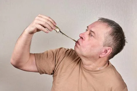 A man pulls out a smelt fish gnawed to the bone with his hand Stock Photos