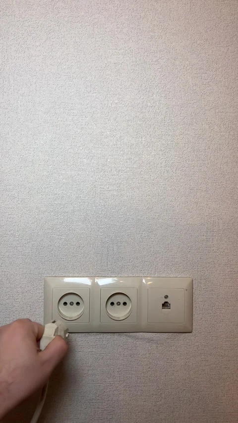 Man pulls out white plug from an extension cord from wall socket Stock Footage 300652587