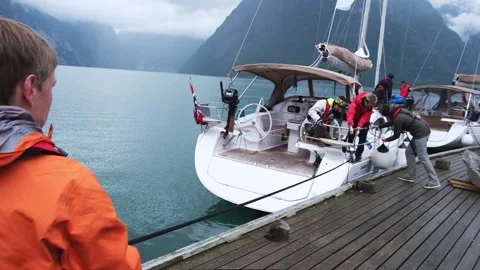 Man pulls rope while team adjusts mooring buoys on yacht Stock Footage 168376919