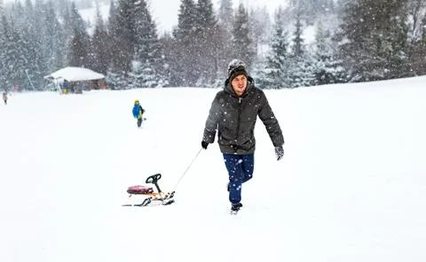 Man pulls sled in the snow, winter forest snowfall snowflakes, play fun activ Stock Photos