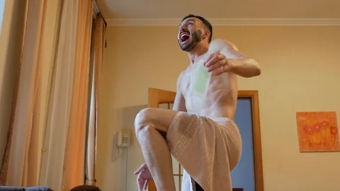 A man pulls a strip for depilation and falls on the bed with a cry of pain. 4k Stock Footage 111812355