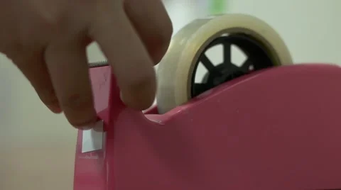 A man pulls tape off of a tape dispenser close up shot Stock Footage 49127027