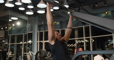 Man pulls weight exercise 4k gym video. Male training back muscles on machine Stock Footage 71798297