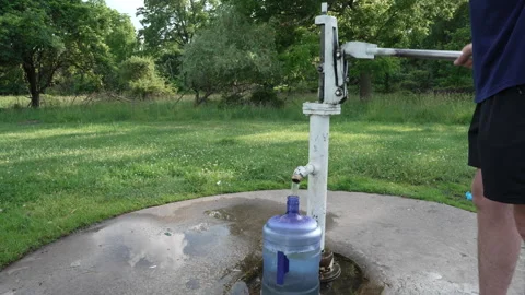 Man pumping fresh water into a large jug at a park Vídeo Stock 338119967