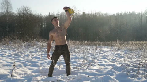 Man pumping up muscles with kettlebell in winter Video stock 147222437