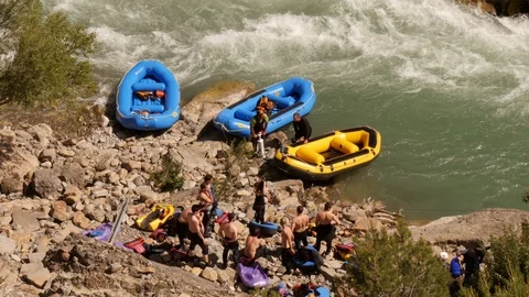 Man pumping up a raft at the river prior to start of  river rafting tour Stock Footage 98307202