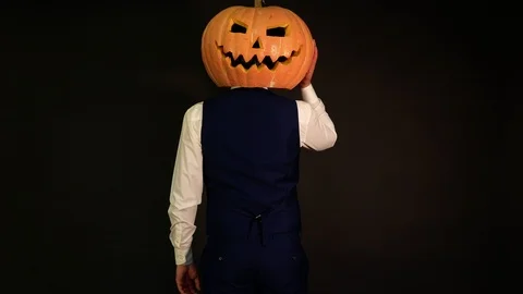 A man with a pumpkin head lost his face but found it on the back of his head. Stock Footage 116230913