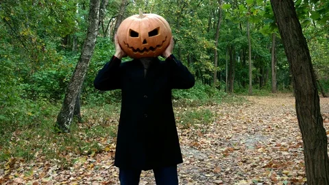 A man with a pumpkin on his head. He grabs his head and waves it. Stock Footage 116494070
