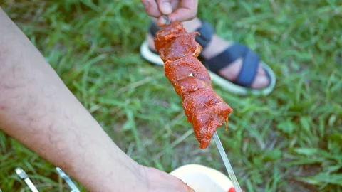 A man pushed through pieces of raw meat with a skewer. Cooking kebab outdoors Stock Footage 118200439