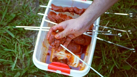 A man pushed through pieces of raw meat with a skewer. Cooking kebab outdoors Stock Footage 118200750