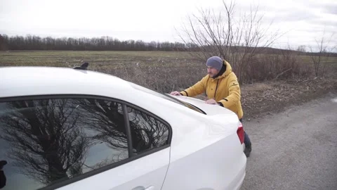 A man pushes a broken down car. Calling the insurance company Stock Footage 264094947