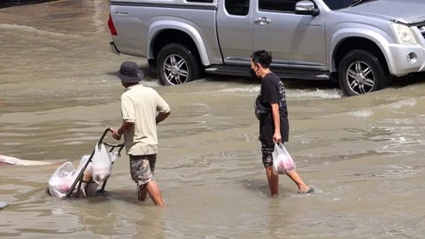 A man pushes a cart with full plastic bags on a flooded street Stock Footage 223377184