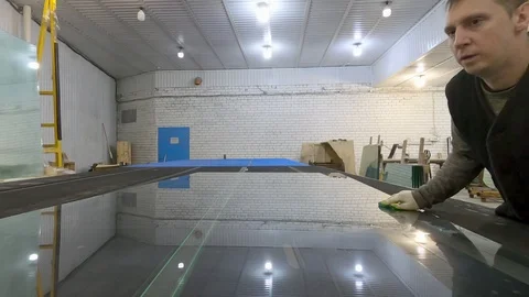 The man pushes the glass sheet on the table for overcutting. Stock Footage 124115751