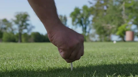 A man pushes a golf tee into the turf then sets a ball on it Stock Footage 158896307