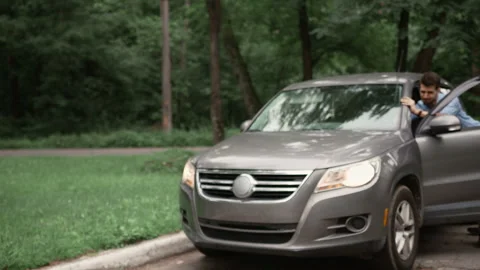 Man pushes his car down the road after the engine overheats. Driver trying  Stock Footage 268503502