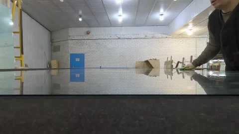 A man pushes a large sheet of polished glass on the table. 스톡 동영상 124275854